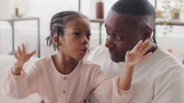 Afro amerikan yetişkin adam Afrikalı baba siyah büyükbaba evde kanepede oturuyor küçük kız çocukla sohbet ediyor, bebek haberi paylaşıyor, aile iletişimi kuruyor.