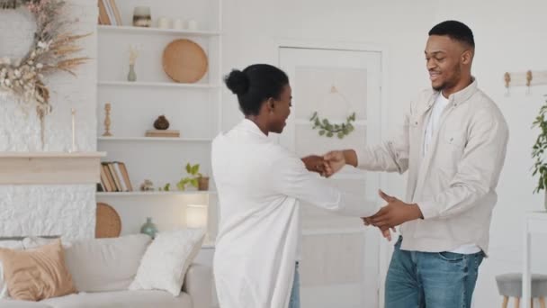 Casal africano futuros pais afro mulher grávida e homem étnico preto família dançando em casa sala de estar celebrando a gravidez marido gira círculos encantadora esposa segurando abraço de mão abraçando — Vídeo de Stock