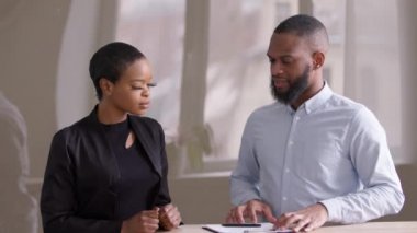 Afrikalı kadın, Afrikalı erkek finans danışmanı emlakçı iş adamı yönetici iş ortağıyla ofisinde kağıt satın alma ortaklığı anlaşması imzalıyor.