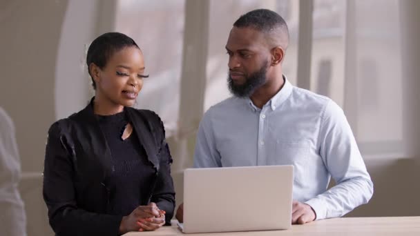 Успешные партнеры коллеги африканский черный бизнесмен и афро-этническая деловая женщина обсуждают проект глядя на ноутбук, женщина-менеджер представляет стартап боссу на заседании офиса мозгового штурма — стоковое видео