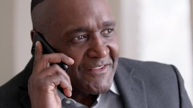Erkek portresi. Yetişkin orta yaşlı iş adamı. 50 'lerin Afrikalı patronu, afro ofis çalışanı. Cep telefonu danışmanlığı yapıyor.