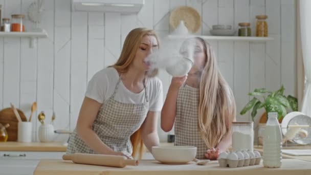 Kaukasisk familj ensamstående mor mamma med barn tonåring flicka dotter ha kul i hemmet kök lek matlagning blåser mjöl i luften från järn sikt skratta underhållning på helgen kock mat baka tillsammans — Stockvideo