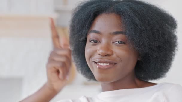 Retrato de la joven chica africana feliz con el pelo rizado mirando la cámara disparar gesto pistola dedo, primer plano de la cara femenina con sonrisa dentada sincera, mujer étnica negra fingiendo pistola de mano de tiro — Vídeos de Stock