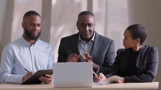 Αφρικανοί συνεργάτες επιχειρηματικών ομάδων νέοι afro επιχειρηματίας και ενήλικος μαύρος εργοδότης ακούγοντας ώριμο αφεντικό ηγέτης κοιτάζοντας σημειώσεις γραφής laptop σε σημειωματάρια διαβούλευση brainstorming — Αρχείο Βίντεο
