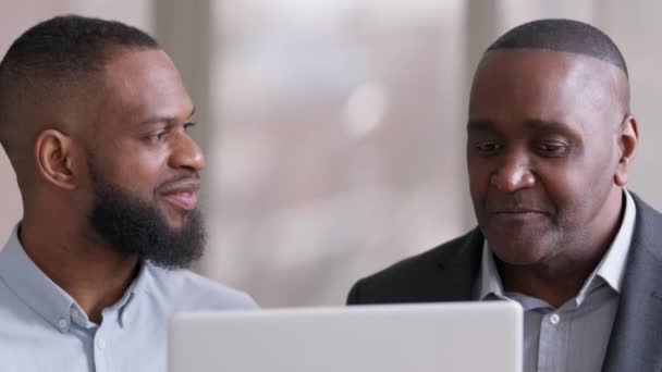 Retrato de dos colegas profesionales africanos socios de negocios afro hombres maduro jefe inversor senior sacudiendo la cabeza sí y joven adulto negro étnico gerente mirando la pantalla de la computadora portátil presentación — Vídeos de Stock