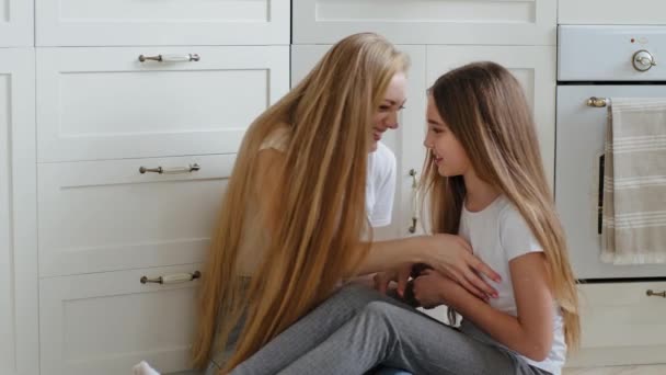 Ευτυχισμένος καυκάσιος αγάπη ανύπαντρη μητέρα ενήλικη γυναίκα με μακριά μαλλιά νταντά babysitter κάθεται στο πάτωμα στο σπίτι με χαριτωμένο έφηβος κόρη γαργαλώντας το κορίτσι του σχολείου αγγίζοντας το παιδί διασκεδάζοντας αγκαλιάζει αγκαλιά γέλιο — Αρχείο Βίντεο
