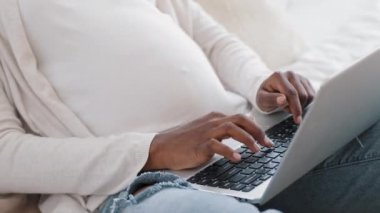 Yakın plan Afrikalı hamile kadın elleri klavyede yazı yazan göbekli kadın sohbet için dizüstü bilgisayar kullanıyor. Tanımlanamayan Afro-Afrikalı kadın uzaktan ürün alışverişi yapıyor.