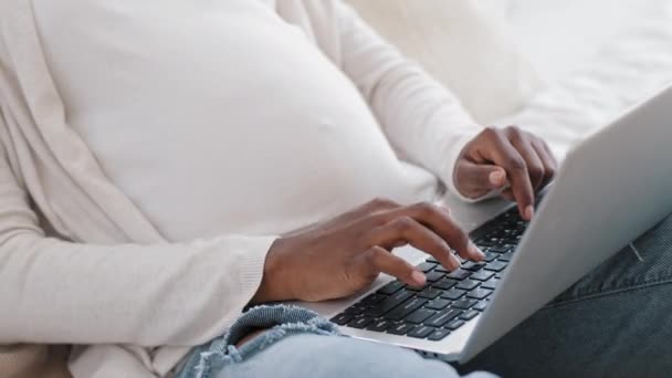 Detailní africká těhotná žena ženské ruce s břichem psaní na klávesnici používá notebook pro chatování. Nerozpoznatelná budoucí matka afro černá dáma pracující na dálku objednávky produkty nakupování on-line — Stock video