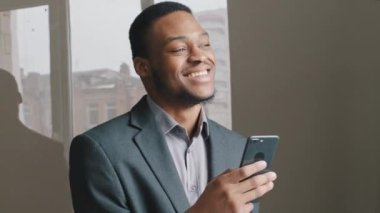 Dijital uygulamalarda çalışan heyecanlı siyahi adam akıllı telefon iyi internet haberleri okuyor, mutlu Afrikalı adam zafer kazanmaktan çok mutlu bir şekilde telefon ekranına bakıyor. Milenyum iş adamı mobil teknoloji kullanıcısı