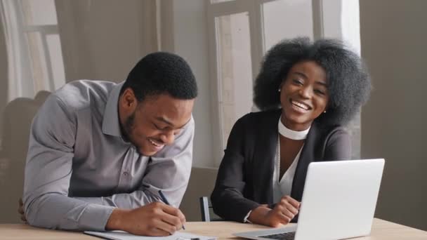 Happy positive young creative African American man, woman employees cooperating talking working together at workplace, smiling coworkers discussing planning business project in corporate teamwork — Stock Video