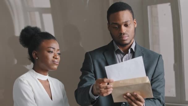 Joven afroamericano de 25 años concentrado sosteniendo un documento en papel sintiéndose infeliz con noticias negativas. Empleado decepcionado recibe notificación de despido del jefe. Triste mujer desesperada perdiendo trabajo — Vídeo de stock