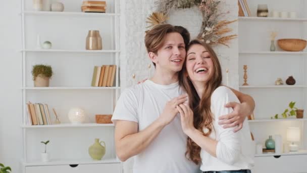 Blank getrouwd stel familie echtgenoot jong mooi vrouw meisje vrouw vriendin en duizendjarige man man man vriend knuffelen knuffelen staan binnen thuis praten dromen lachen lachen — Stockvideo