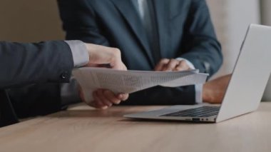 Yakın çekim erkek eli kağıt rapor sözleşmesi tutuyor ofis masasında tartışan iki çok ırklı iş adamı Kafkas projesini tartışıyor ve Afrikalı patronun baş parmak gösterdiğine işaret ediyor
