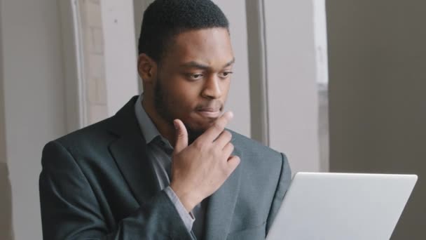 Fokuserad afrikansk amerikansk affärsman student hålla hand på hakan förlorad i tankar på jobbet med bärbar dator, allvarlig pensiv man tittar bort tänka på problemlösning söka inspiration nya idéer — Stockvideo