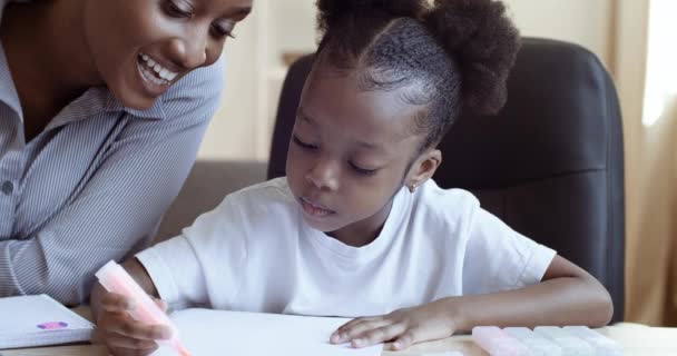 Afrikanische ethnische Mutter Unterricht hilft beim Fernstudium Tochter Kind Hausaufgaben zu machen. Amerikanische Familie verbringt glückliche Zeit miteinander, unterrichtet zu Hause, Kind lernt mit Mutter zeichnen, kreative Aktivitäten — Stockvideo