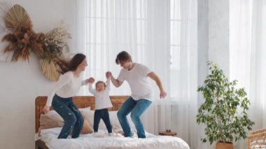 Genç ebeveynler, küçük kızı olan beyaz bir aileyle evlendi. Küçük bir kız çocuğu el ele zıplıyor. Yatak odasında zıplıyor, evde eğleniyor, ebeveynlik ve iletişimin keyfini çıkarıyor.