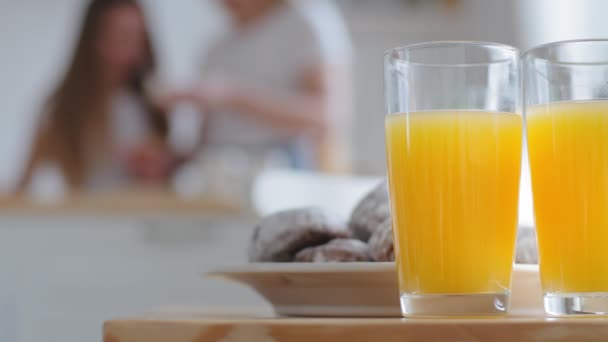 Dois copos transparentes com manga de laranja natural suco de frutas tropicais bebida fica na mesa na cozinha em casa perto de deliciosos biscoitos de chocolate no fundo da família turva, conceito de dieta alimentar saudável — Vídeo de Stock