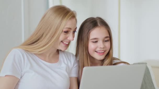 Volwassen mooie moeder volwassen vrouw met dochter tienermeisje samen zitten thuis met behulp van moderne laptop om films te kijken grappige video 's op het web op de website browsen kijken naar computerscherm lachen — Stockvideo