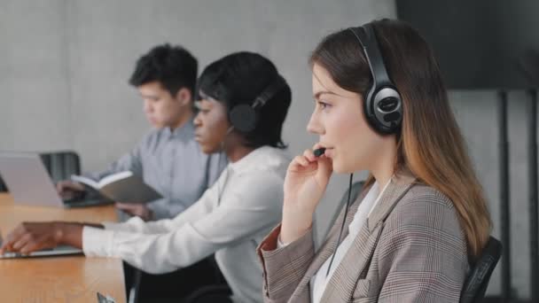 Allvarlig kaukasiska kvinnliga call center agent bära trådlöst headset med bärbar dator tittar på skärmen konsult kund med online-problem gör videosamtal på kontoret, fokuserad kvinna arbetar i stödtjänst — Stockvideo