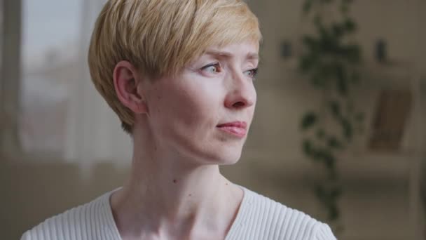 Pensive caucasian mature woman 35-40s female sad upset housewife with short hair looks out window contemplates thinking dreaming about future experiencing deeply in thoughts planning sitting at home — Stok video