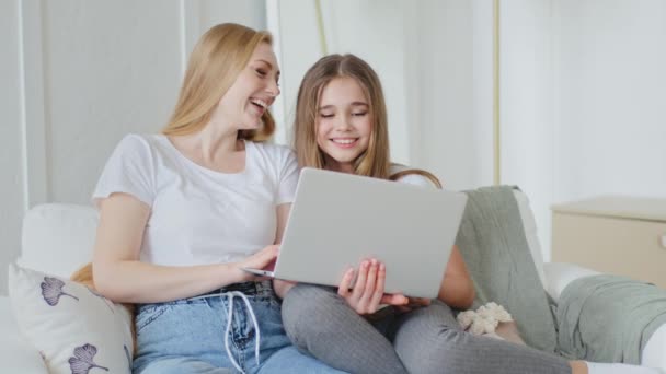 Ενήλικες μητέρα και έφηβος κορίτσι παιδί κάθεται μαζί στον καναπέ χρησιμοποιώντας σύγχρονο φορητό υπολογιστή βλέποντας βίντεο αστείες εικόνες σε απευθείας σύνδεση surfing internet δυνατά γελώντας ειλικρινά διασκεδάζοντας περιήγηση στο διαδίκτυο — Αρχείο Βίντεο