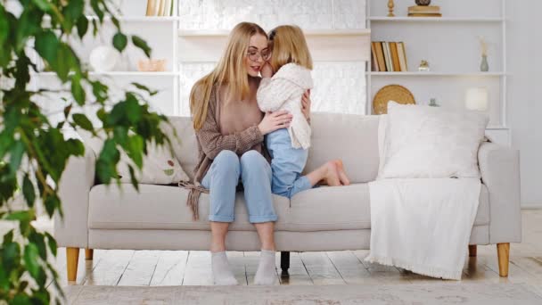 Caring mother babysitter listens to secrecy information with curiosity hears secret of talking little girl daughter preschooler whispers into mom ear, Caucasian family sitting on sofa sharing news — Stock Video