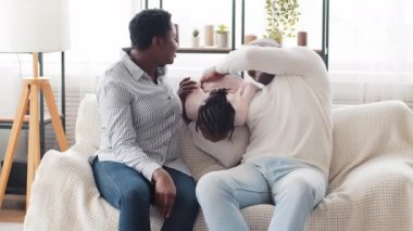 Afro-Amerikan ailesi, Afrikalı kadın anne ve olgun zenci erkek koca konuşuyor kanepeye oturmuş küçük kız çocuk kız çocuk kanepeye zıplıyor güçlü baba gıdıklıyor bebeği havada baş aşağı kaldırıyor