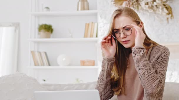 Retrato jovem adulto menina loira caucasiano mulher freelance feminino estudante usa óculos olha para o laptop funciona com computador se sente cansado dor de cabeça desconforto nos olhos sintoma de enxaqueca massagens templos — Vídeo de Stock