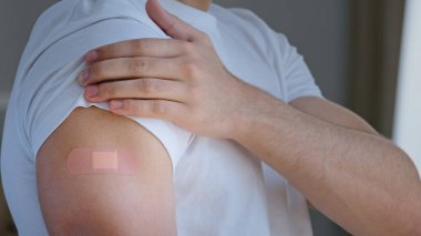 Cropped shooting arabian young man, portrait male Spaniard ethnic guy patient looking at shoulder with medical plaster on mark of injection smiling satisfied vaccination immunization against covid