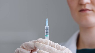 Unrecognizable woman doctor nurse medical worker scientist wears latex gloves holds syringe with needle in hands splashes of liquid antibiotic medicine injection vaccination with coronavirus vaccine