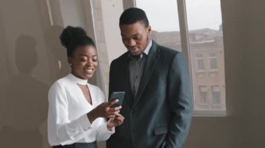 Mutlu meslektaşlar konuşuyor. Akıllı telefonlara bakıp gülüyorlar. Ofiste durmuş komik uygulamalar kullanıyorlar. Gülümseyen profesyonel insanlar cep telefonlarında internet üzerinden video izlemekten zevk alıyorlar.