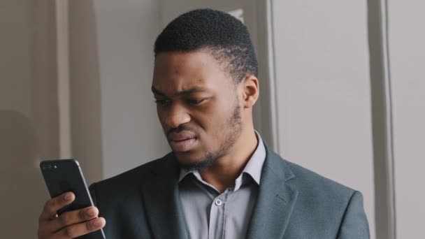 Απογοητευμένος Αφροαμερικάνος που κοιτάζει την οθόνη του κινητού, διαβάζει άσχημα νέα στο κινητό μήνυμα, αισθάνεται σοκαρισμένος. Ανήσυχος επιχειρηματίας έχασε χρήματα σκεπτόμενος ξαφνικά προβλήματα μετά την ανάγνωση sms — Αρχείο Βίντεο