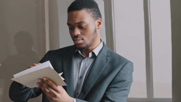 Focalisé jeune homme d'ethnicité africaine 25s tenant document papier dans les mains, se sentant malheureux échec de l'examen stressé, prêt bancaire notification de la dette d'argent, des nouvelles négatives dans la correspondance, avis d'expulsion — Video