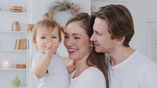 Ritratto famiglia caucasica giovane madre padre millenario amorevole genitori tenere bambina figlia guardare macchina fotografica sinceramente sorridere agitando mani ciao saluto bambino dice prima parola donna sorpreso — Video Stock