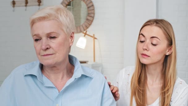 Stödjande medkännande kärleksfull vuxen dotter smeker axeln av desperat stressad medelålders mor, sitter i vardagsrummet. Ung snäll omtänksam kvinna visar stöd till mogen äldre mamma — Stockvideo