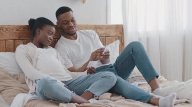 Müstakbel Afrikalı evli çift kanepeye uzanmış, ultrason filmi seyrediyor. Doğmamış çocuk, şefkatli koca afro adam, zenci kadının sevgili karısının karnını okşuyor.