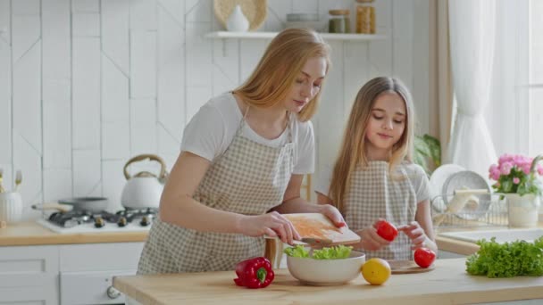 Kaukasiske midaldrende familie mor og pige teenager barn datter forbereder frisk sund velsmagende salat sammen hjemme køkken skære grøntsager peber, tomater og salat taler madlavning nyder – Stock-video