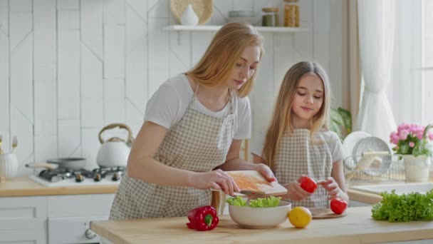 Caucásico mediana edad familia madre y niña adolescente niño hija preparando fresco saludable sabrosa ensalada juntos en casa cocina cortar verduras pimienta, tomates y lechuga hablando cocinar disfrutando — Vídeo de stock