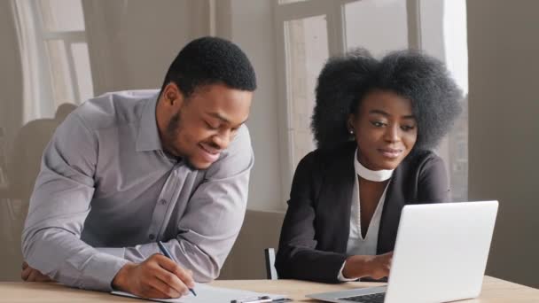 Lächelnde junge afrikanische Büroangestellte diskutiert neue Ideen, plant Projekte mit männlichen Kollegen im Büro. Millennial-Frau kooperiert bei Treffen mit Finanzberaterin — Stockvideo