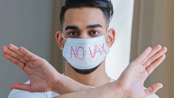 Ritratto di uomo ispanico arabo in maschera protettiva medica con iscrizione nessun vaccino incrocia le braccia di fronte a lui rifiutando di dimostrare il rifiuto di protesta di essere vaccinato contro l'influenza coronavirica covid — Foto Stock