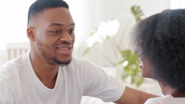Portrait african man ethnic black guy chatting talking speaking with unrecognizable woman with afro hairstyle curly hair unknown mixed race girl sitting home indoors casual conversation communication