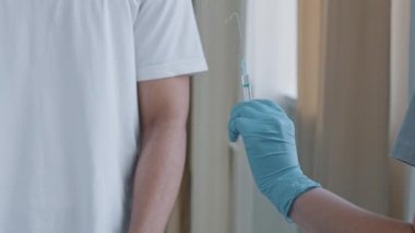 Lateks eldivenli kadın doktor elinde şırınga ile ilaç aşısı tutuyor, afro amerikalı hasta önüne avuç içi koyuyor aşı karşıtlığını reddediyor.