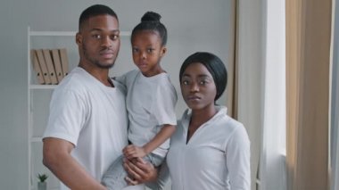 Ciddi afro-amerikan aile ebeveynleri ve küçük kızları kameraya bakıyor. Önlerine avuç içlerini koyuyorlar. Yasaklama konusunda anlaşmazlık çıkarıyorlar.