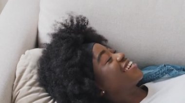 Gülümseyen Afro-Amerikan genç kız öğrenci iş gününün sonunda yastığa konuyor. Milenyum melezi kadınlar hafta sonunun, tatilin, uzun zamandır beklenen dinlenmenin tadını çıkarıyor.