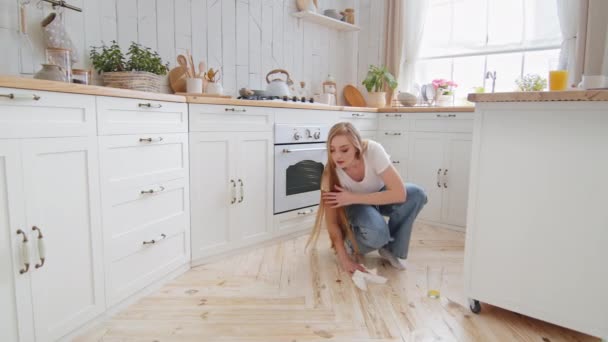 Mujer adulta ama de casa rubia con pelo largo lava el piso en la cocina toallitas húmedas mancha en parquet de jugo derramado de vidrio con toallas de papel con trapo blanco cuidar de la limpieza de la casa — Vídeos de Stock