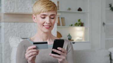 Cep telefonu ve kredi kartı taşıyan mutlu kadın alışverişçi e-bankacılık uygulamasında kolay cep telefonu ödemesi yapıyor. Moda ürünleri alıyor, internet üzerinden para harcıyor, web sitesi kullanıyor, sanal hizmetlerden memnun.
