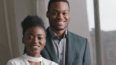 Kendine güvenen birkaç bin yıllık Afro-Amerikan kadın ve takım elbiseli adam ofiste poz veren mutlu etnik genç profesyonel, öğrenciler veya iş adamları iş portresini kapatıyor.