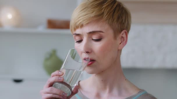 Close up view woman reduces thirst takes a sips drinking glass of natural or mineral water normalizing bowel function. Dehydration prevention, skin and health care, healthy life habit benefits concept — Stock Video