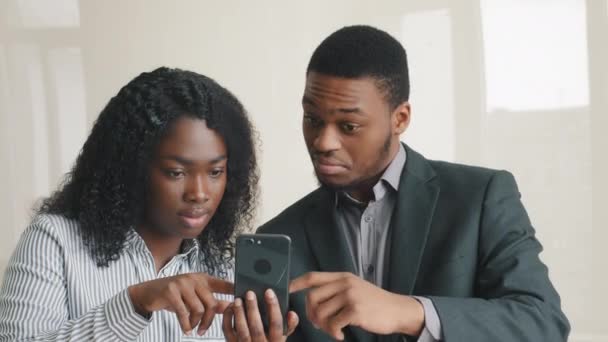 Överraskad upphetsad svart man och kvinna tittar på mobiltelefon skärmen överlycklig läsa goda internet nyheter förvånad över seger framgång, bra erbjudande, reklam information som visar tummen upp känns glad — Stockvideo