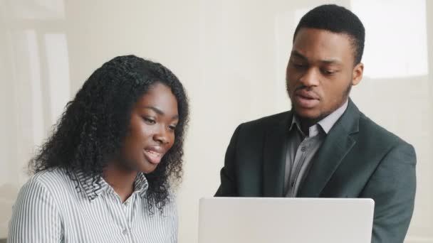 Professionell manlig mentor lärare hjälpa afrikansk amerikansk kvinnlig praktikant med företagets programvara online jobbkurs på jobbet. Allvarligt olika medarbetare prata samarbeta med datorn i office lärling — Stockvideo